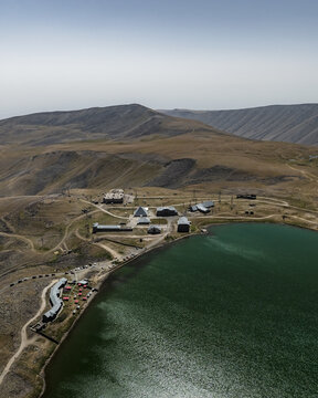 Aerial view of the tranquil, emerald waters of Lake Kari meeting the rugged, sun-baked terrain near the observatory, Lake Kari, Aragatsotn Province, Armenia.