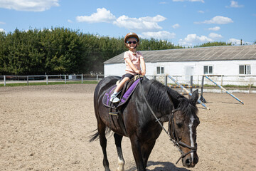 Little girl riding a horse alone in outdoor arena