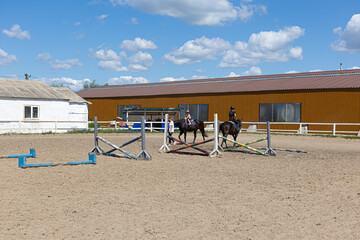 Little girl learning horseback riding with trainer on farm arena