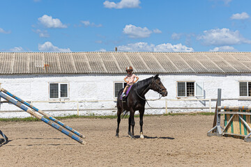 Child horse riding lesson with instructor in sunny outdoor equestrian arena