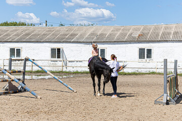 Child horse riding lesson with instructor in sunny outdoor equestrian arena