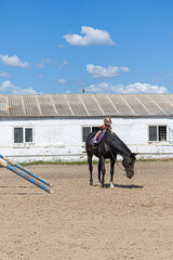 Child horse riding lesson with instructor in sunny outdoor equestrian arena