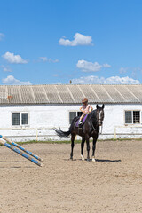 Child horse riding lesson with instructor in sunny outdoor equestrian arena