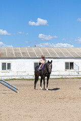 Child horse riding lesson with instructor in sunny outdoor equestrian arena