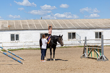 Child horse riding lesson with instructor in sunny outdoor equestrian arena