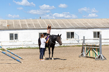 Child horse riding lesson with instructor in sunny outdoor equestrian arena