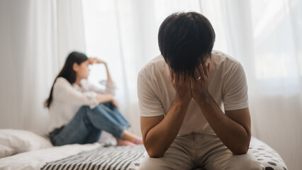 Heartbroken man covering face after argument with girlfriend in bedroom