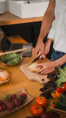Couple peeling potatoes together in the kitchen surrounded by fresh vegetables