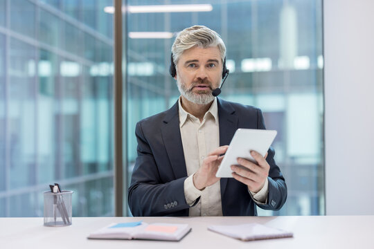 Professional man with headset using a tablet in a modern office