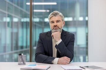 Confident businessman sitting in modern office with thoughtful expression