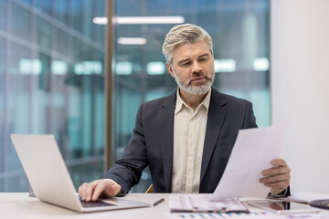 Professional businessman analyzing documents in modern office workspace