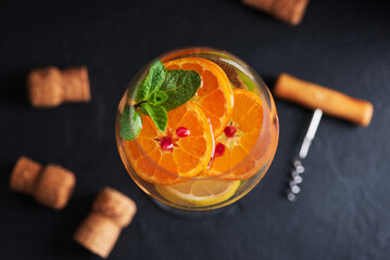 Sangria with citrus fruits and mint, corks and a corkscrew on a dark table with wine bottles. Top...