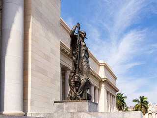 Bronze statue of woman in front of the 1929 National Capitol of Cuba seen during a sunny day,...