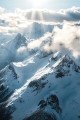 Drone shot above snowy peaks with sunlight breaking through clouds