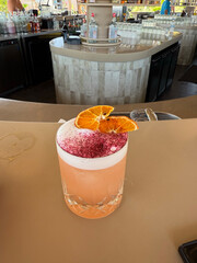 Refreshing red cocktail with ice and mint garnish in a glass, placed on a white surface, possibly a...