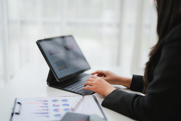 Businesswoman analyzing financial charts and graphs on digital tablet and paperwork