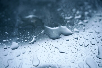 An abstract image of raindrops on a reflective metallic surface. The cool tones and natural pattern...
