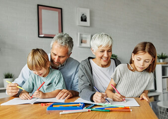 Portrait of grandparents and grandchildren having fun together reading and writing homework at home