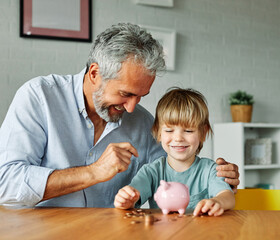 Grandparent And His Grandson Putting Coin Money In Piggybank  At Home. Personal Savings, Bank Safety And Financial Investments Concept