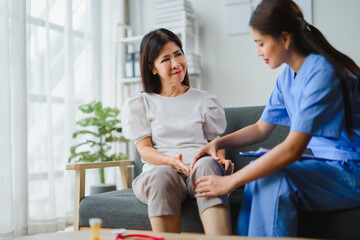 Young nurse checking senior woman knee in nursing home