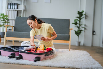 Young Woman Checking her Checklist While Packing a Suitcase for Travel