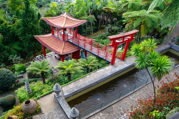Beautiful Japanese Monte Palace tropical garden in Madeira with greenery, red bridge and red pagoda. Location: Funchal, Madeira. Artistic picture. Beauty world