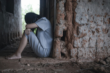 Despair young girl sits crying in a ruined old house in forest. Arrested for human trafficking