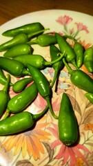 A closeup of fresh green chili peppers on a decorative plate
