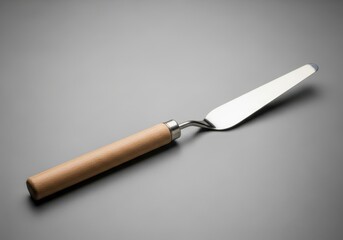 Shiny palette knife resting on a minimalistic neutral gray surface studio shot