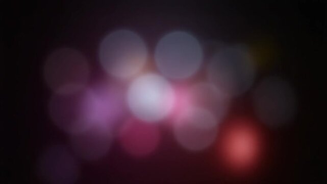 Soft colorful bokeh lights rotating on black in a seamless loop.