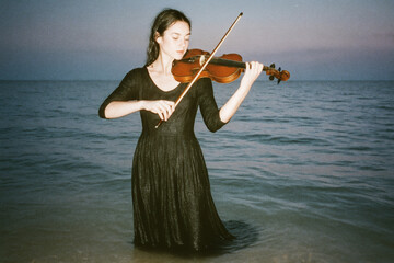 Dreamlike portrait of woman playing violin near the ocean, surreal atmosphere with cinematic artistic concept.