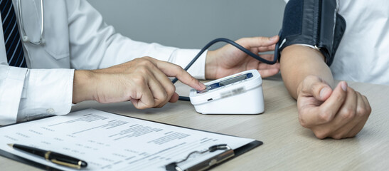 The doctor is checking blood pressure and is also using a stethoscope, to check for the cause of the patient's illness and to advice health care at hospital office