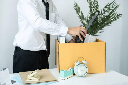 Business man employee packing stationery box and picking up personal belongings into brown cardboard box