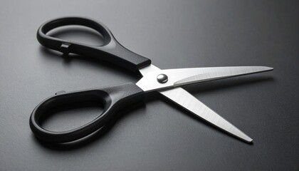 Metallic scissors with black handles on dark textured surface, blades slightly open, sleek design highlighted by reflective light