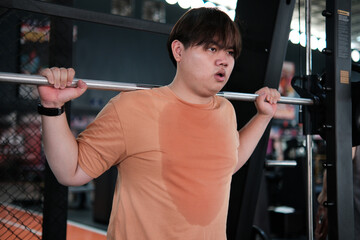 Overweight Man Doing Squats with Barbell at Gym. Strength Training and Sweat Effort