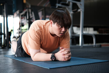 Overweight man plank on mat at gym, core strength, balance. Concept of fitness training, weight loss, and healthy lifestyle.