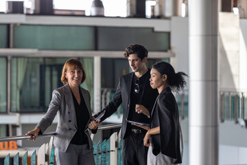 Group discussion between senior female manager and her team members from different ethnicities and cultures on business and management at a terrace outside of the building. Team work across genders.