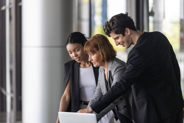 Conversation or group discussion among business team members from different generations, cultures, and diverse ethnicities outside of the main office. Group of people use computer to get information