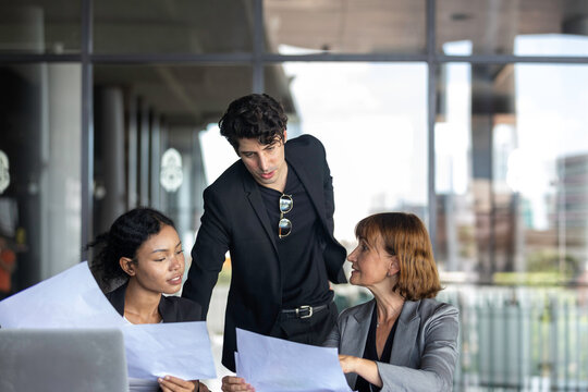Conversation or group discussion among business team members from different generations, cultures, and diverse ethnicities outside of the main office. Group of people use computer to get information