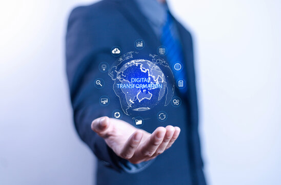 Businessman presents digital transformation concept with holographic globe and technology icons symbolizing innovation, data analytics, cloud computing and future business strategies.