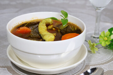 Sour Fish Soup is a thick soup made with chopped greens and carrots, topped with fish pieces,...