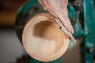 Closeup of carpenter sanding wooden product using sandpaper on a lathe. High quality photography