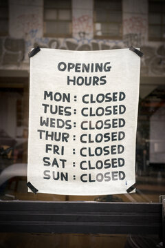 Handmade sign in shop window humorously listing all days as closed for business