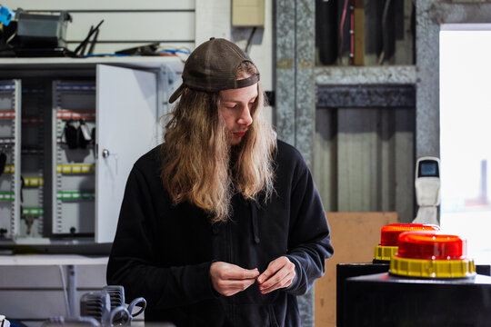 young Aussie man working in mechanics workshop building part of light bar of vehicle