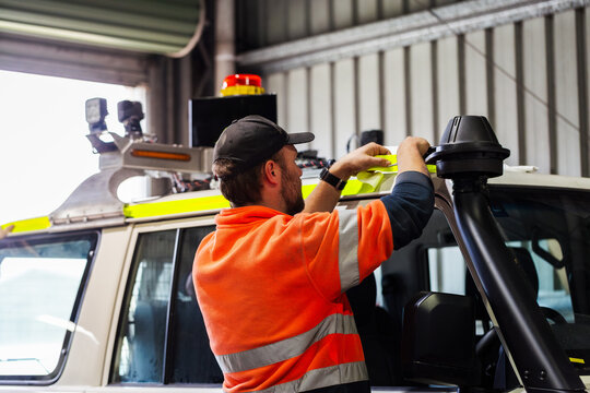 mechanic applying high vis reflective tape to mining fleet vehicle in workshop shed