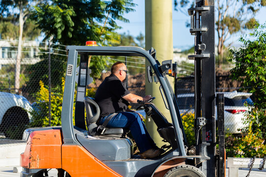 forklift operator driving forklift outside in industrial area
