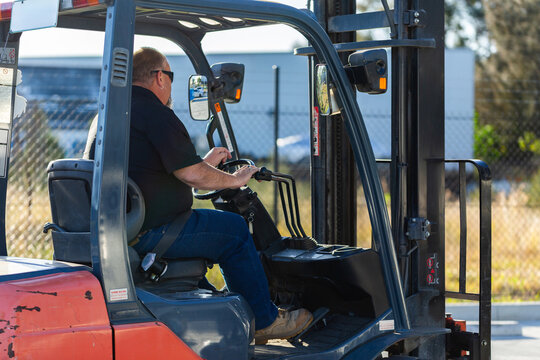forklift operator driving forklift outside in industrial area