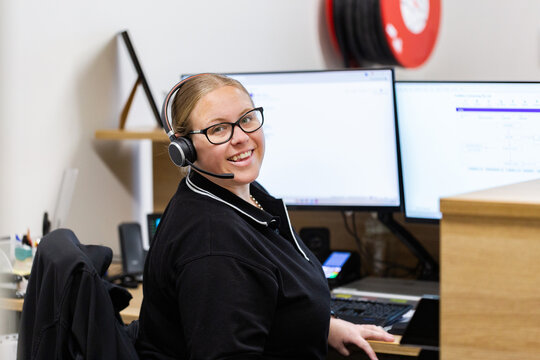 female administrate staff lady sitting by computer at front desk office