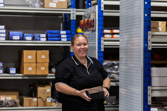 woman in storeroom at mechanics workshop looking thorough boxes of spare parts