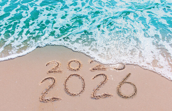 Message Year 2025 replaced by 2026 text written on beach sand background. Good bye 2025 - 2026 happy New Year coming concept.  top view.